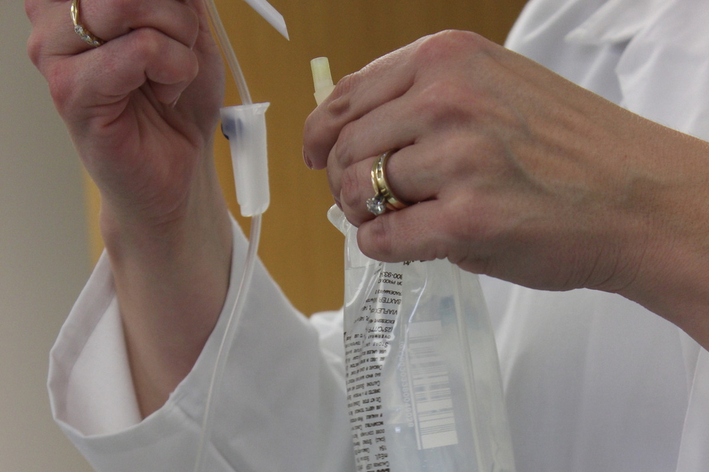 nurse or doctor holding an IV getting it ready to use on a patient