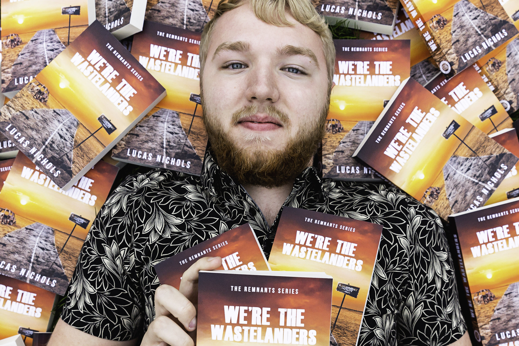 Lucas Nichols lying in a pile of his recently published book 