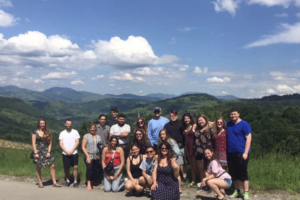 Group of students posing in Romania - can see the students with mountains in the background