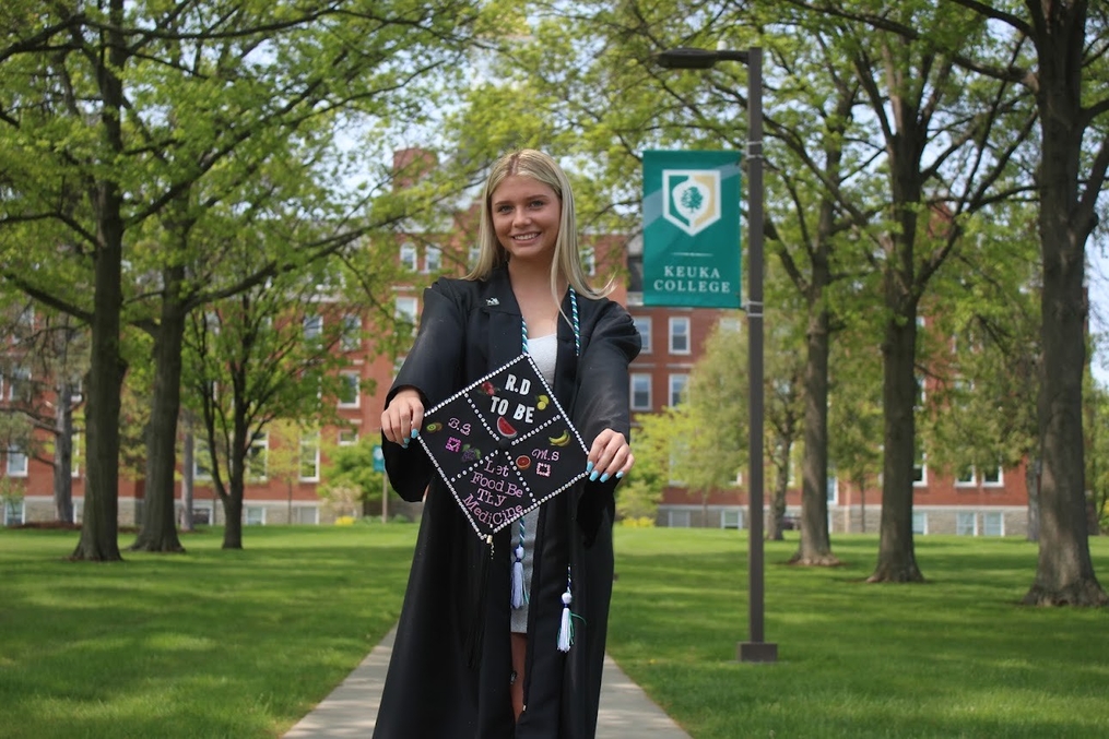 Cierra Gottler in graduation gown on chapel walkway 